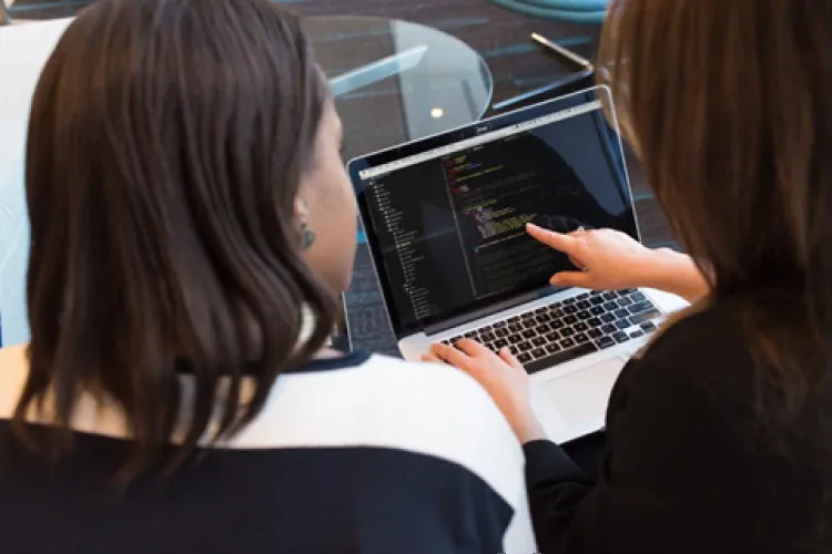 Two developers reviewing code together on a laptop