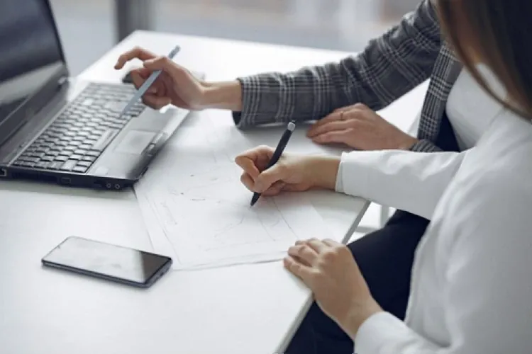 Colleagues planning a hiring brief with notes and a laptop